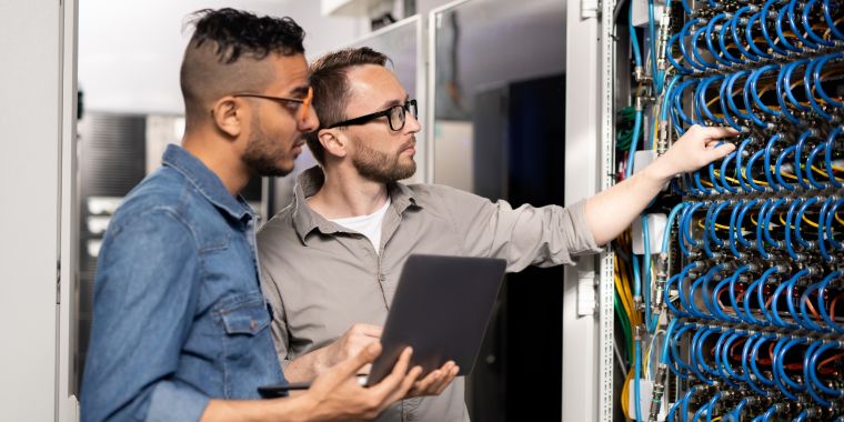 two male engineers inspecting a rack full of network cables