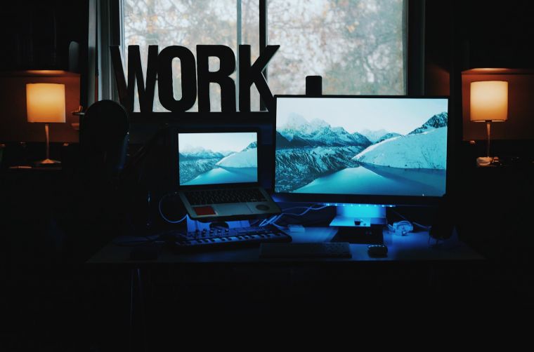 Two Screens showing a sign to the left of them saying WORK  - Photo by Patrick Tomasso on Unsplash