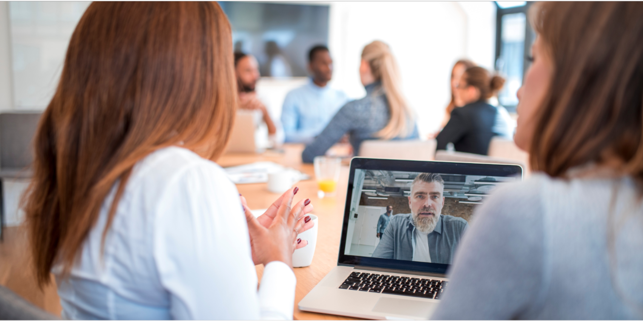 2 women in a meeting with a man on the laptop in a collaboration/co-working space